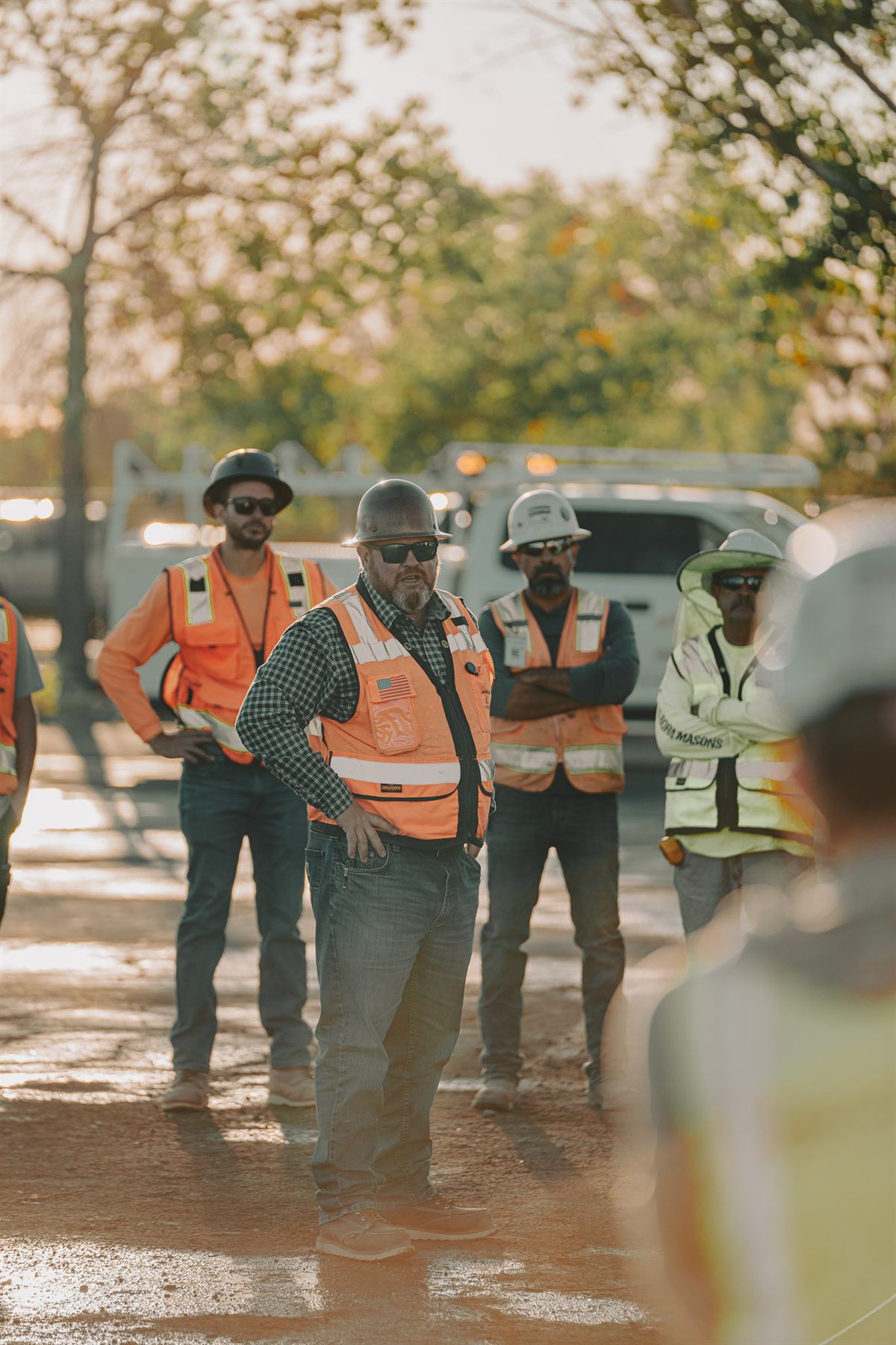 A Pokrajac superintendent leading a tailgate safety meeting with crew at golden hour.