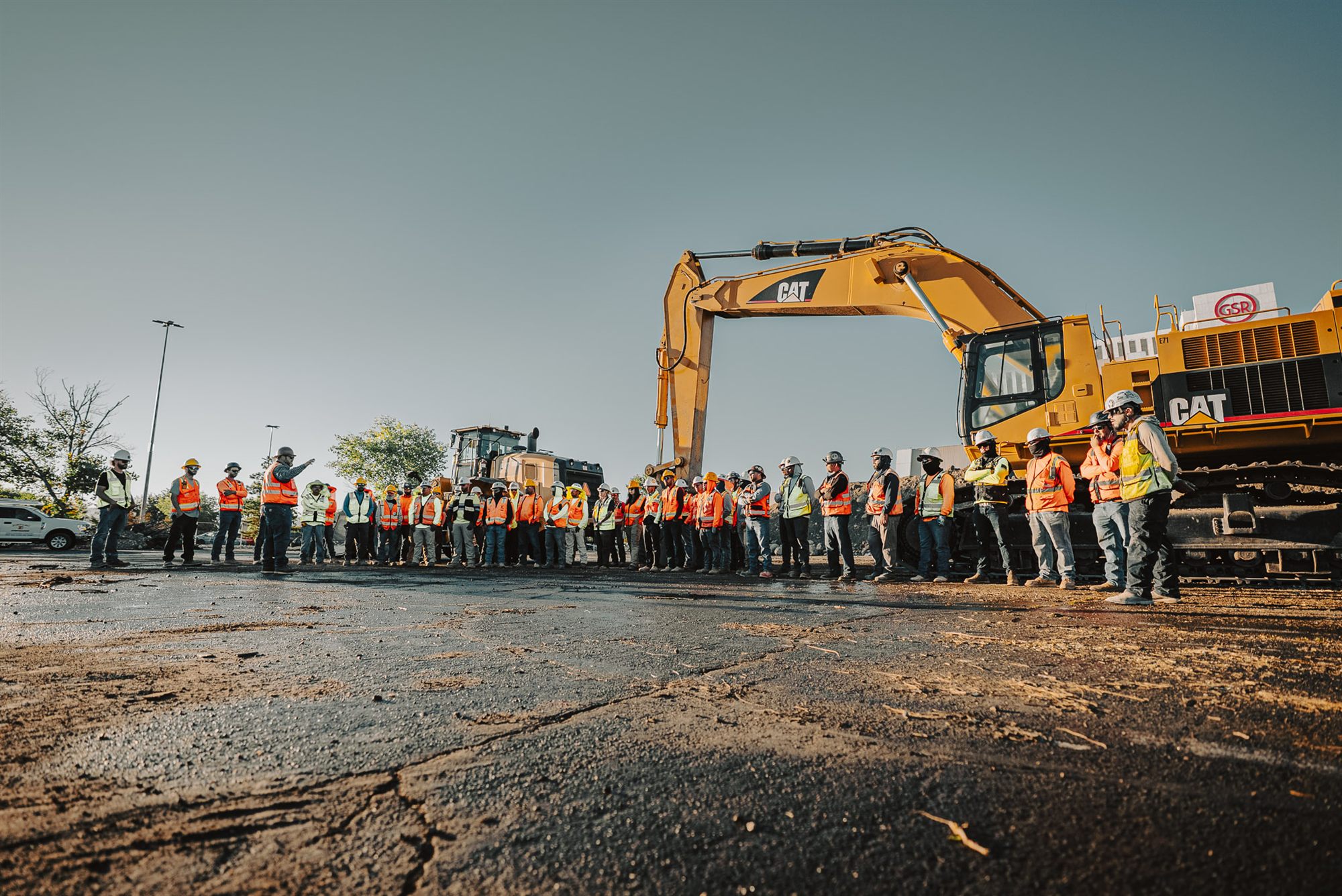 A full Pokrajac crew lined up on site in front of a Caterpillar excavator at the start of shift.