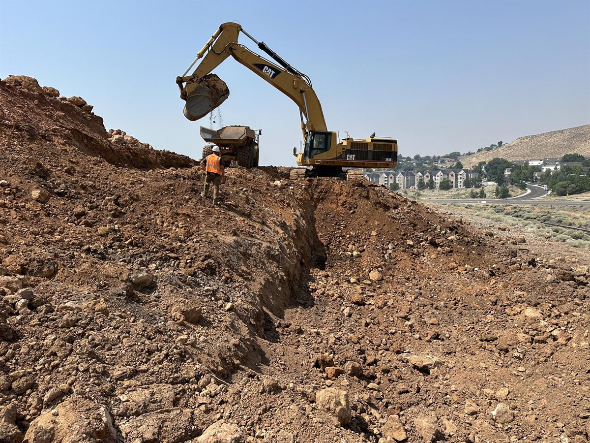 An excavator loading a haul truck on a cut slope at Reno Air Logistic Park.