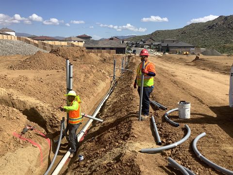 Crew setting conduit and pipe in an open joint trench.